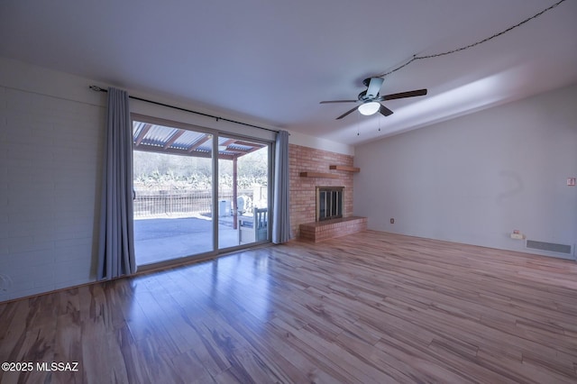 unfurnished living room with ceiling fan, a fireplace, and light wood-type flooring