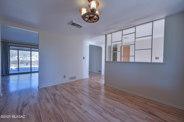 empty room with an inviting chandelier and light hardwood / wood-style flooring