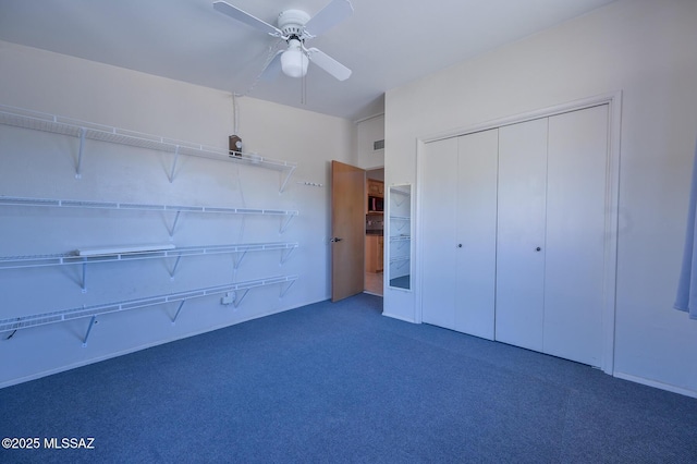 unfurnished bedroom with dark colored carpet, a closet, and ceiling fan