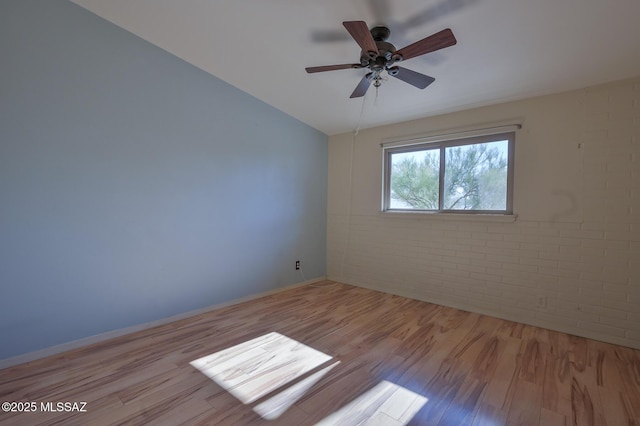 unfurnished room featuring light hardwood / wood-style floors, ceiling fan, lofted ceiling, and brick wall