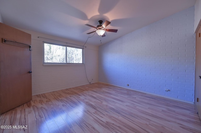 spare room with ceiling fan, brick wall, and light hardwood / wood-style flooring