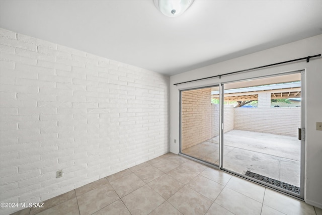 unfurnished bedroom with light tile patterned floors, brick wall, and a closet