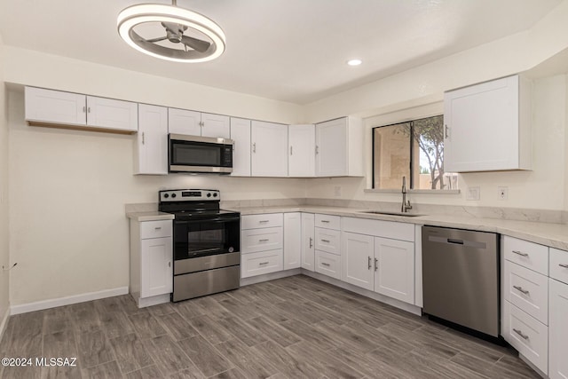 kitchen featuring sink, white cabinets, wood-type flooring, and appliances with stainless steel finishes