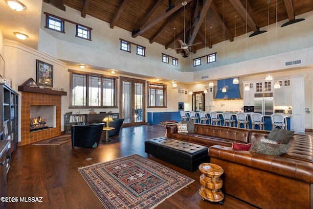 living room featuring beamed ceiling, ceiling fan, dark wood-type flooring, and high vaulted ceiling