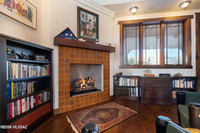 living area with a tile fireplace and dark hardwood / wood-style flooring