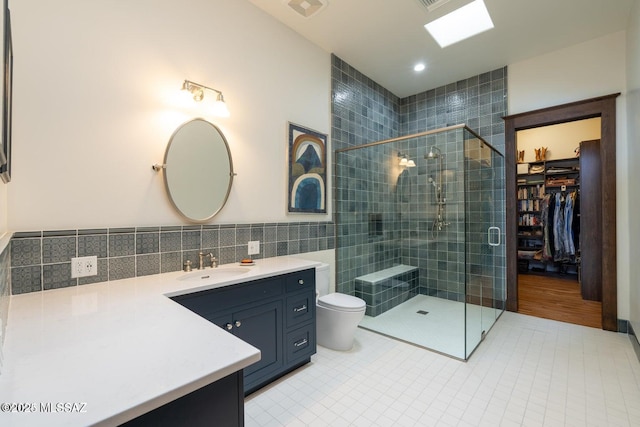 bathroom featuring vanity, a shower with door, tile patterned flooring, toilet, and tile walls