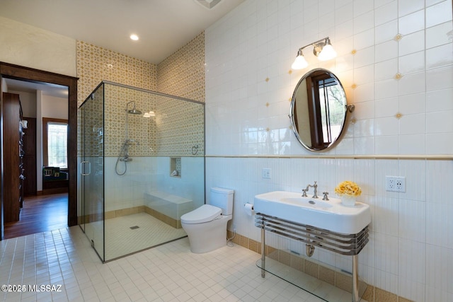 bathroom featuring tile patterned floors, toilet, walk in shower, and tile walls