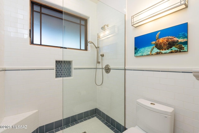 bathroom with tiled shower, tile walls, and toilet