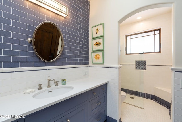 bathroom featuring tile patterned flooring, vanity, toilet, and tile walls