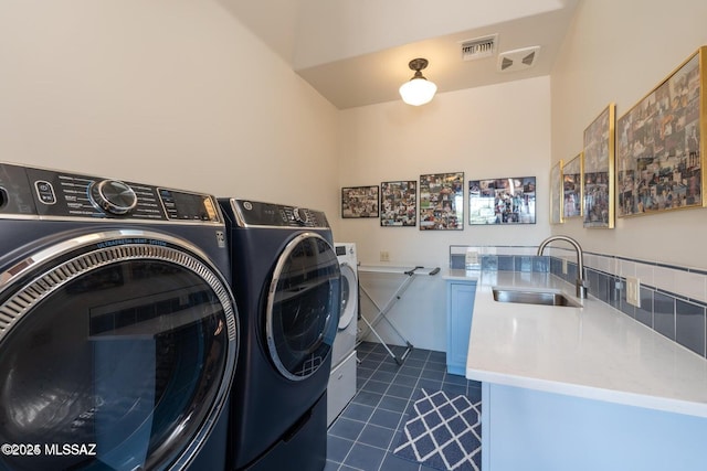 clothes washing area with separate washer and dryer, dark tile patterned flooring, and sink