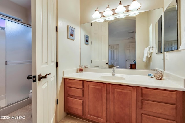 bathroom featuring vanity, tile patterned flooring, toilet, and a shower with shower door