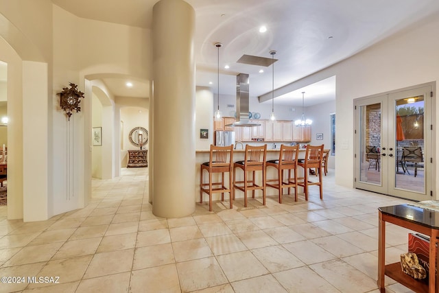 kitchen featuring a center island, decorative light fixtures, french doors, island exhaust hood, and a kitchen breakfast bar