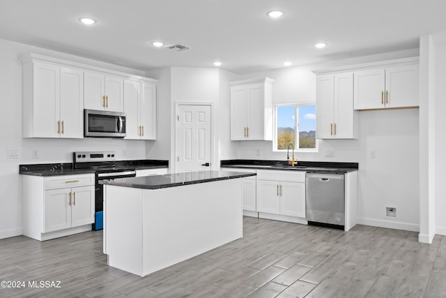 kitchen featuring a center island, white cabinets, sink, appliances with stainless steel finishes, and light hardwood / wood-style floors