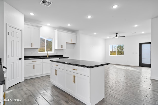 kitchen with plenty of natural light, ceiling fan, white cabinetry, and light hardwood / wood-style flooring