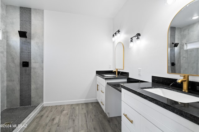 bathroom with hardwood / wood-style flooring, vanity, and tiled shower