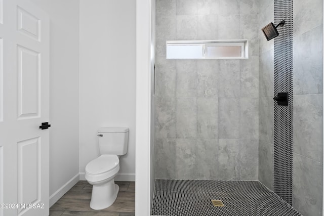 bathroom with a tile shower, hardwood / wood-style floors, and toilet