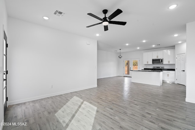 unfurnished living room featuring ceiling fan, french doors, and light hardwood / wood-style flooring