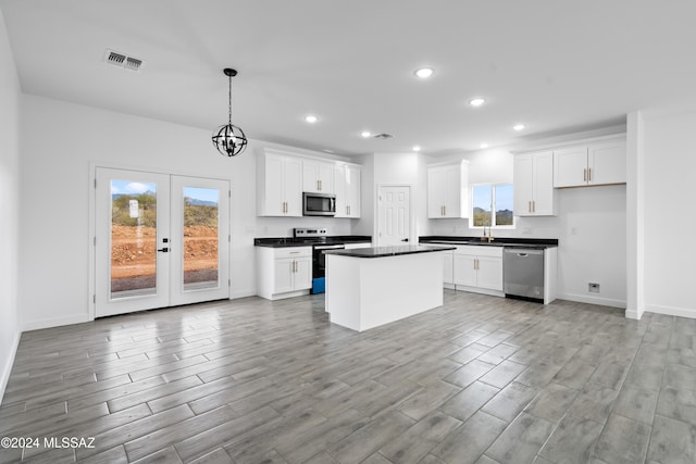 kitchen featuring white cabinets, a center island, stainless steel appliances, and hanging light fixtures