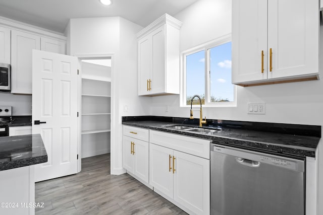 kitchen featuring sink, light hardwood / wood-style flooring, dark stone counters, white cabinets, and appliances with stainless steel finishes