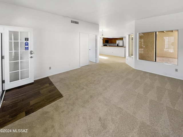 unfurnished room featuring carpet and a notable chandelier