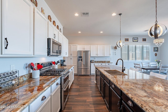 kitchen featuring pendant lighting, white cabinets, sink, and appliances with stainless steel finishes