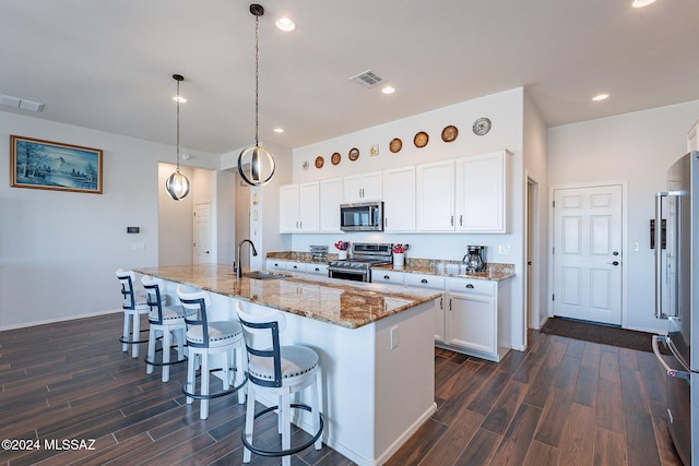 kitchen with white cabinets, an island with sink, pendant lighting, and appliances with stainless steel finishes