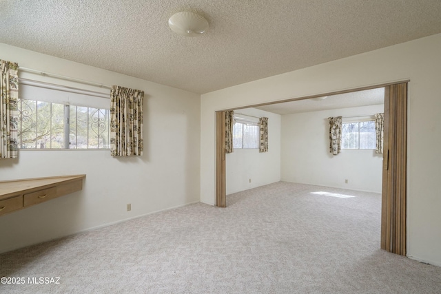 carpeted spare room featuring a healthy amount of sunlight and a textured ceiling