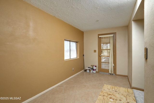 interior space featuring light tile patterned floors, baseboards, and a textured ceiling