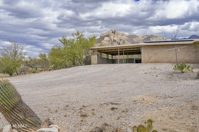 view of property exterior with a mountain view, driveway, brick siding, and a carport