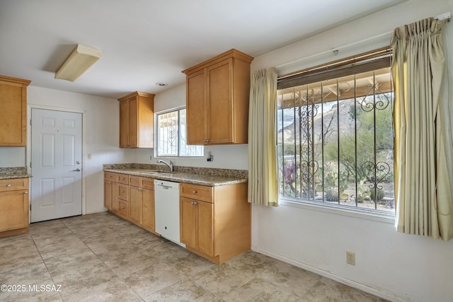 kitchen with brown cabinets, a sink, light stone counters, baseboards, and dishwasher