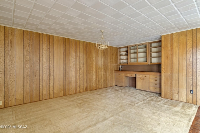 interior space featuring a notable chandelier, built in desk, and wooden walls