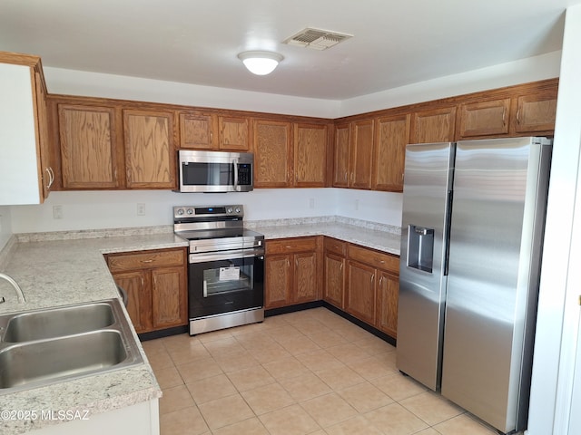 kitchen with light tile patterned floors, stainless steel appliances, and sink