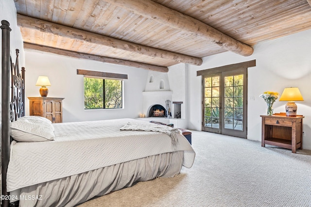 carpeted bedroom with french doors, a large fireplace, access to outside, beam ceiling, and wooden ceiling