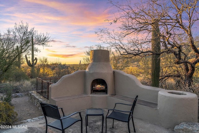 patio terrace at dusk featuring an outdoor fireplace