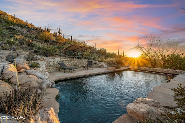 pool at dusk with a patio area