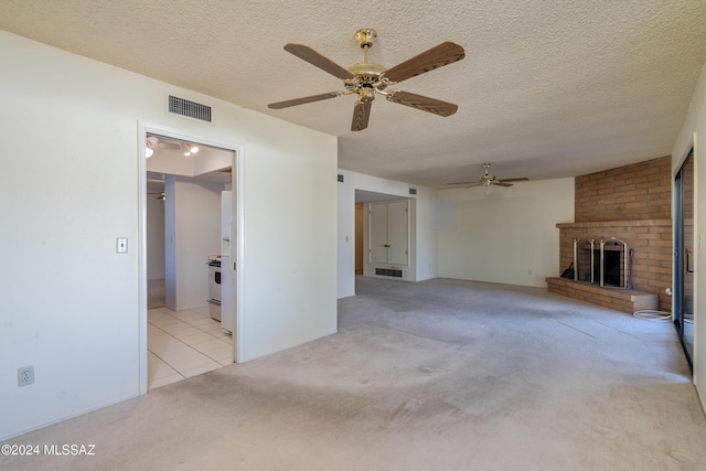 unfurnished living room featuring a brick fireplace, visible vents, light carpet, and a textured ceiling