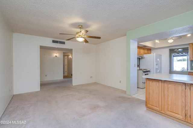 unfurnished living room featuring ceiling fan, a textured ceiling, visible vents, and light colored carpet