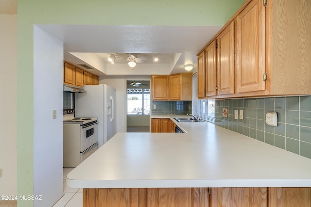 kitchen with under cabinet range hood, a peninsula, white electric range, light countertops, and a raised ceiling