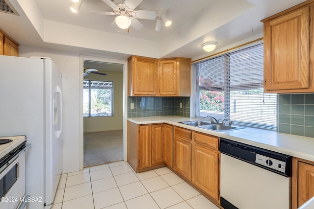 kitchen with light countertops, visible vents, backsplash, a sink, and white appliances