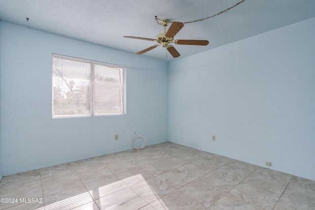 empty room with a textured ceiling and a ceiling fan