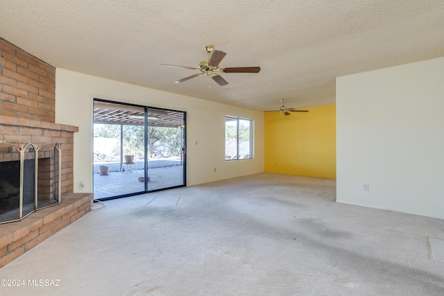 unfurnished living room featuring a wealth of natural light, light colored carpet, a fireplace, and a textured ceiling