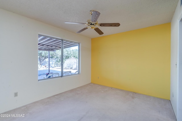 spare room with light carpet, ceiling fan, and a textured ceiling