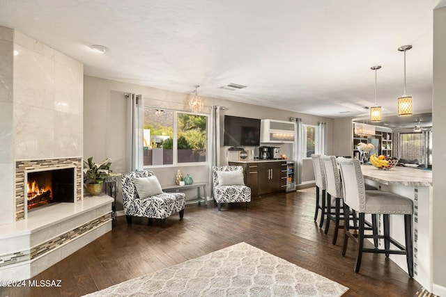 living room featuring a healthy amount of sunlight, beverage cooler, dark hardwood / wood-style floors, and a tile fireplace