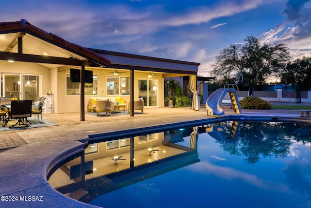 view of swimming pool featuring ceiling fan, outdoor lounge area, a water slide, and a patio