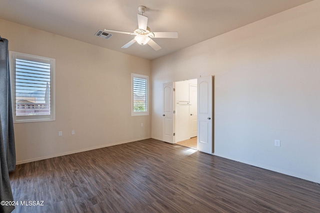 empty room featuring plenty of natural light, ceiling fan, and dark hardwood / wood-style flooring