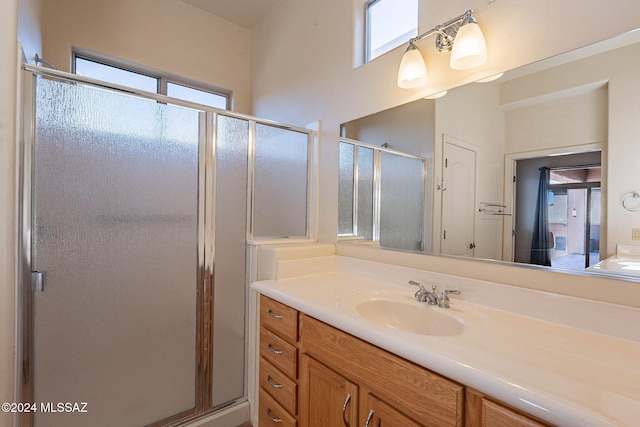 bathroom with vanity, a shower with door, and a healthy amount of sunlight