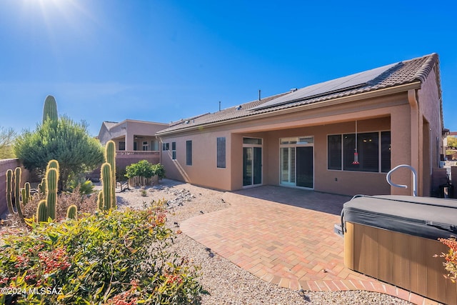 back of house featuring solar panels, a patio, and a hot tub