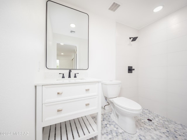 bathroom featuring tiled shower, vanity, and toilet