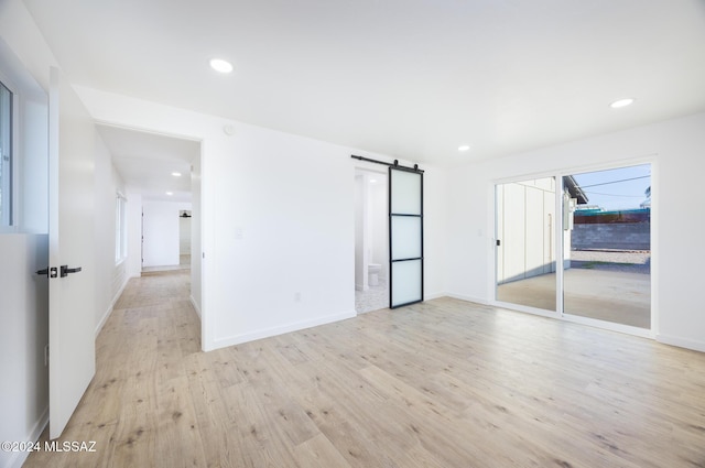 empty room featuring a barn door and light hardwood / wood-style flooring