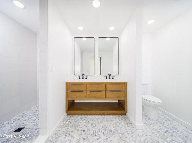 bathroom with tiled shower, vanity, and toilet